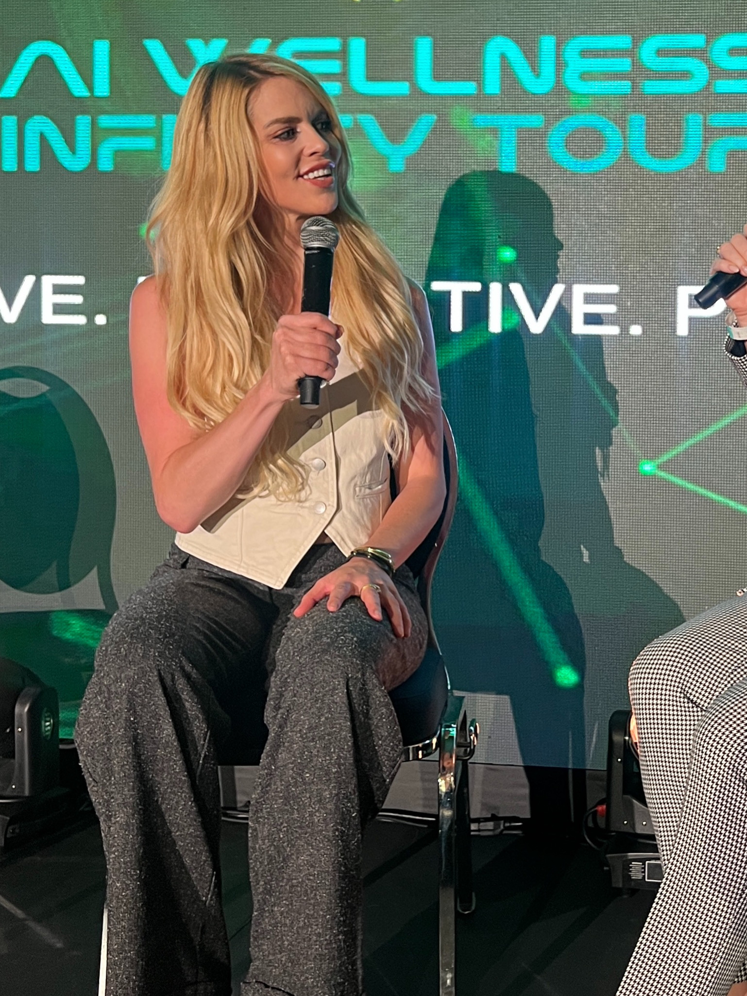 Dr. Paige Roberts on stage with a microphone, speaking at a wellness conference.