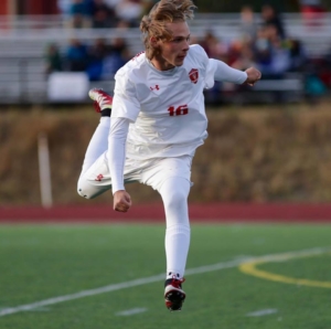 Alex Coffey striking a soccer ball in a Varsity match