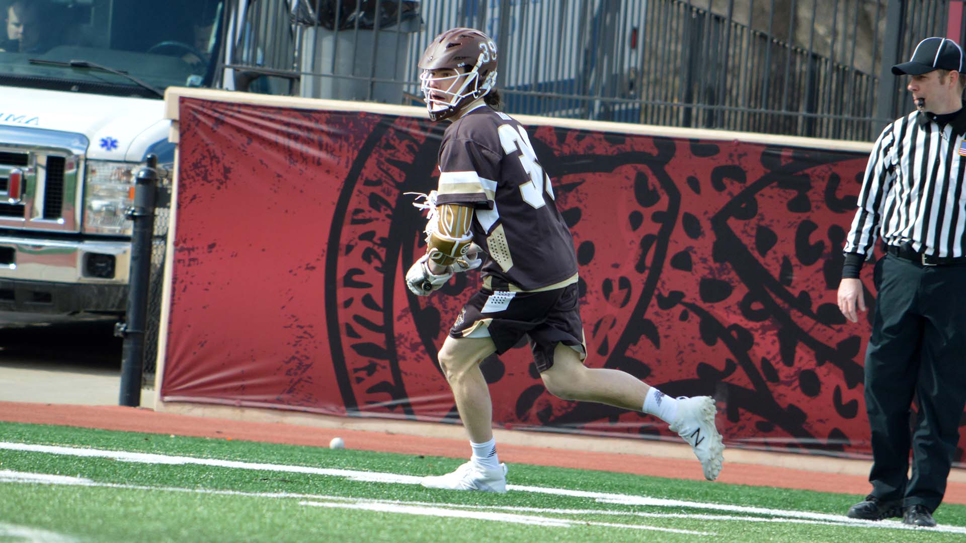 Willy Gunn carrying the ball downfield in a D1 lacrosse game